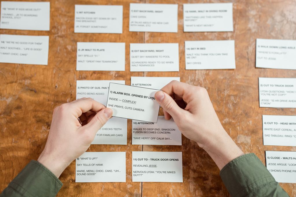 Hands organizing index cards on a desk, focusing on planning, creativity, and workflow strategy.